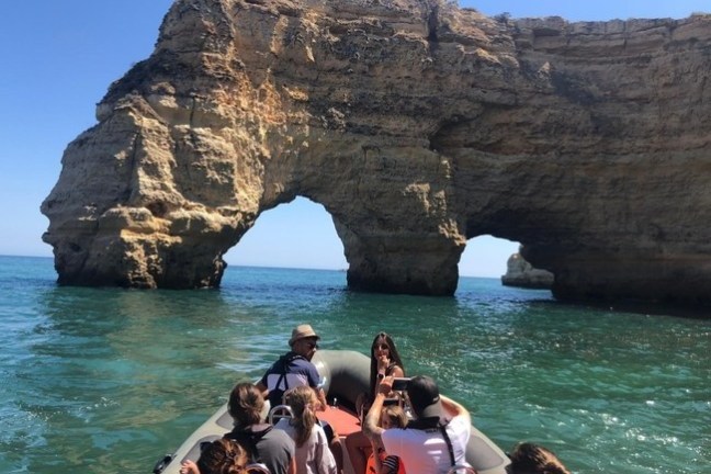 a group of people on a rock next to a body of water