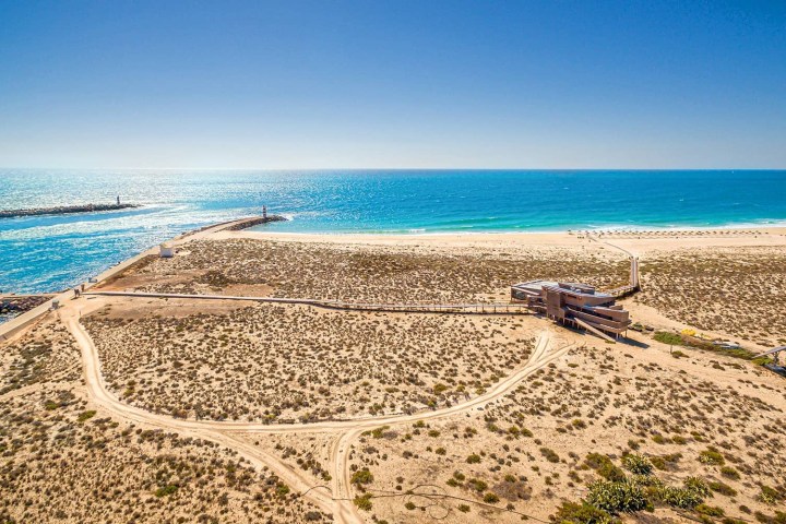 a row of lawn chairs sitting on top of a sandy beach
